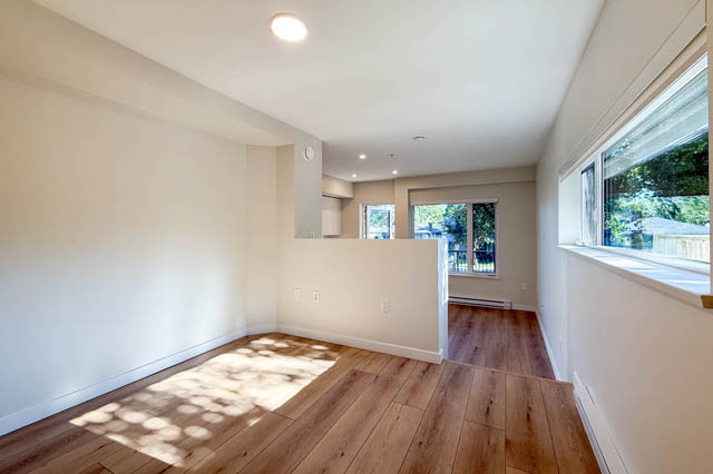Bright living room with hardwood floors and large windows, showcasing a city view. - G 22 - 2070 East 20th Ave, Vancouver East Side