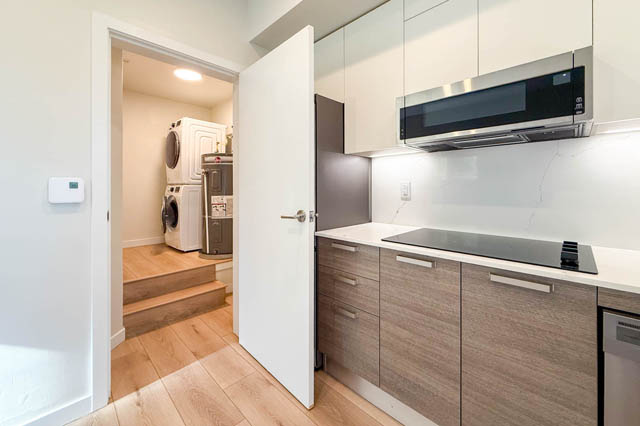 Bright kitchen with white countertops, hardwood floors, and a view of the laundry area. - G 22 - 2070 East 20th Ave, Vancouver East Side