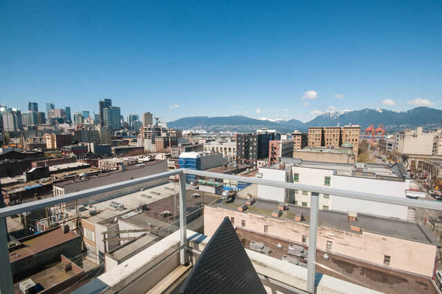 The balcony features a railing, a lounge chair, and a view of city buildings and distant mountains. - 812-189 Keefer Street, Vancouver Downtown