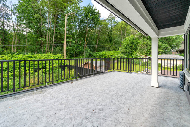 Spacious patio with black railing and lush greenery. - 1-4096 Nithsdale Street, Burnaby