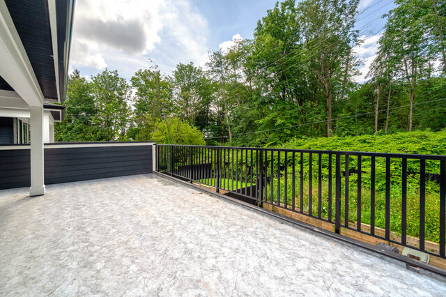 Spacious patio with modern black railings and lush greenery in the background. - 1-4096 Nithsdale Street, Burnaby