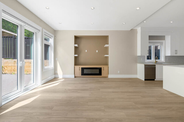 Bright kitchen with hardwood floors and white cabinetry, featuring a large island and ample counter space. - 1-4096 Nithsdale Street, Burnaby