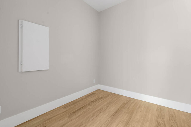 Bright living room with hardwood floors and a minimalist white wall. - 1-4096 Nithsdale Street, Burnaby