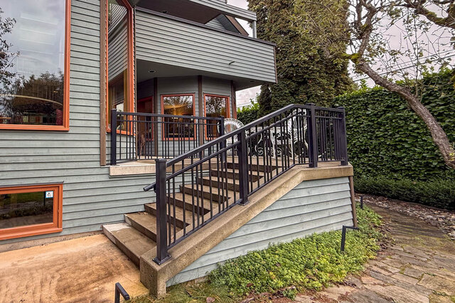 Stylish entryway with modern black railings and concrete steps leading to a cozy, furnished 4-bedroom house on the West Side.