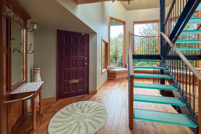 Elegant foyer with glass-topped staircase, hardwood floors, and a view of lush greenery. - 3850 Point Grey Road, Vancouver West Side