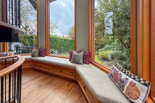 Cozy corner with built-in bench, hardwood floors, and large windows overlooking a lush garden. - 3850 Point Grey Road, Vancouver West Side