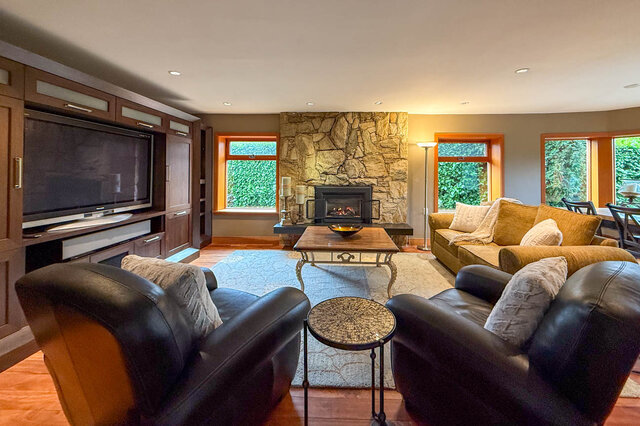 Spacious living room with stone fireplace, large windows, and comfortable seating. - 3850 Point Grey Road, Vancouver West Side