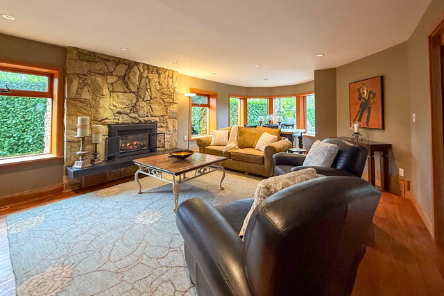 Spacious living room with stone fireplace, hardwood floors, and large windows. - 3850 Point Grey Road, Vancouver West Side