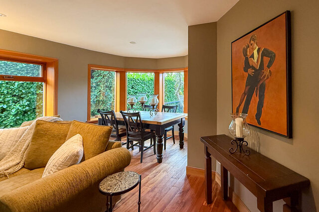 Spacious living room with hardwood floors, large windows, and a vibrant orange painting of dancers. - 3850 Point Grey Road, Vancouver West Side