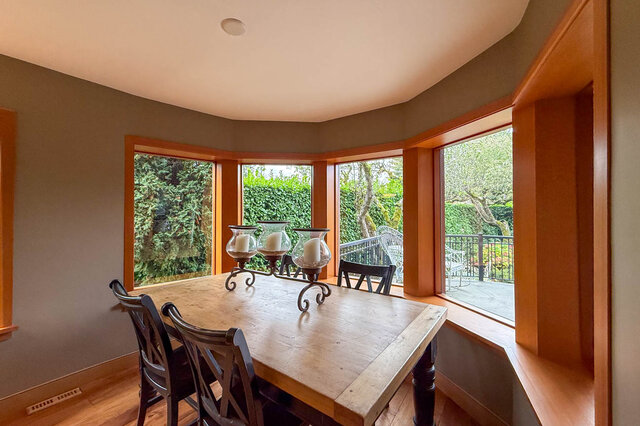 Spacious dining area with bay windows, hardwood floors, and a view of greenery. - 3850 Point Grey Road, Vancouver West Side