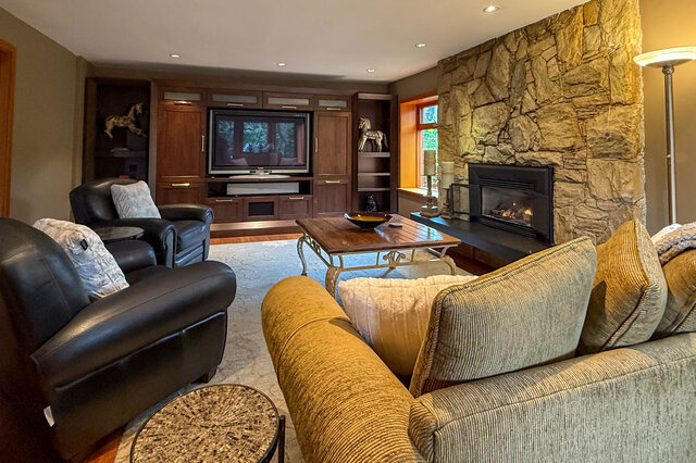 Spacious living room with stone fireplace, leather furniture, and a large flat-screen TV. - 3850 Point Grey Road, Vancouver West Side