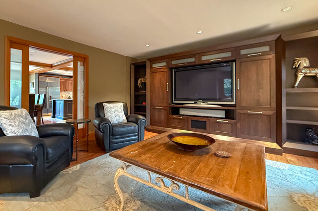 Spacious living room with hardwood floors, a large TV, and comfortable leather furniture. - 3850 Point Grey Road, Vancouver West Side