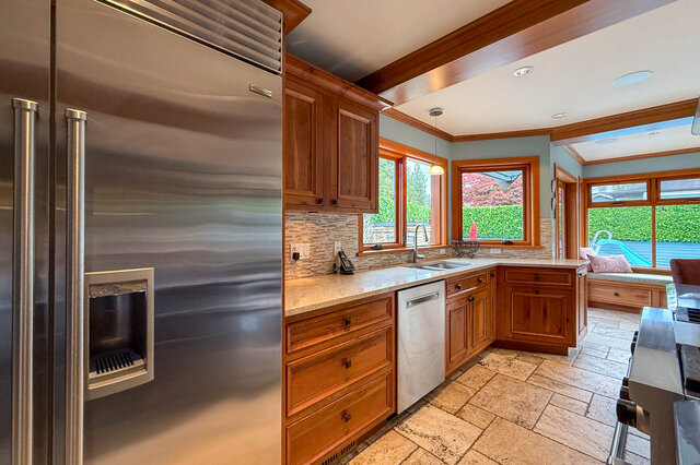 Bright kitchen with wooden cabinets, granite countertops, and a view of greenery outside. - 3850 Point Grey Road, Vancouver West Side