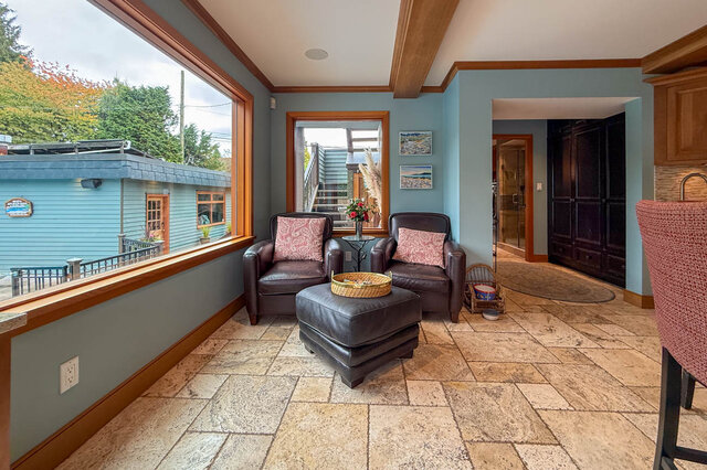 Spacious living room with large windows, stone flooring, and cozy leather seating. - 3850 Point Grey Road, Vancouver West Side