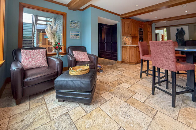 Open-concept living area with tiled floors, leather armchairs, and a kitchen bar. - 3850 Point Grey Road, Vancouver West Side