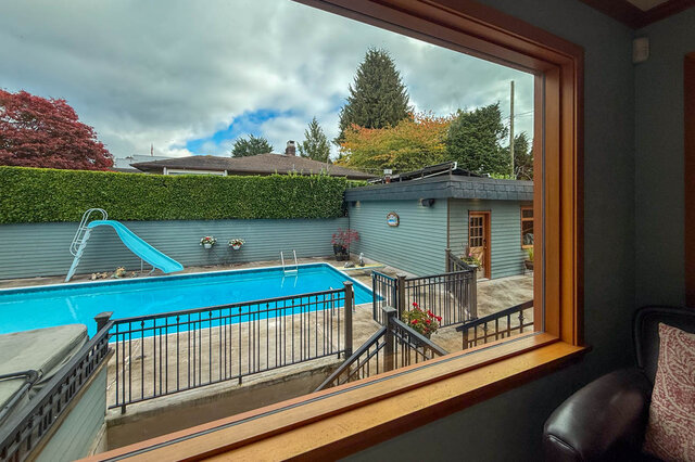 Bright living room with a view of a pool and garden, featuring a cozy corner and a sliding glass door. - 3850 Point Grey Road, Vancouver West Side