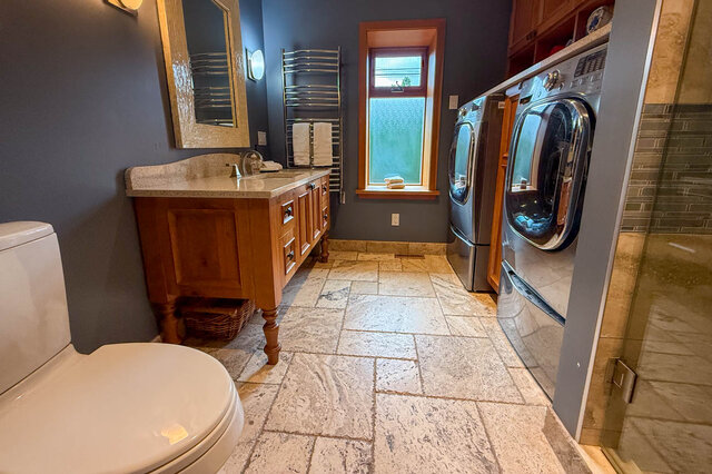 Bathroom with stone countertops, wooden cabinets, and a window with a view. - 3850 Point Grey Road, Vancouver West Side