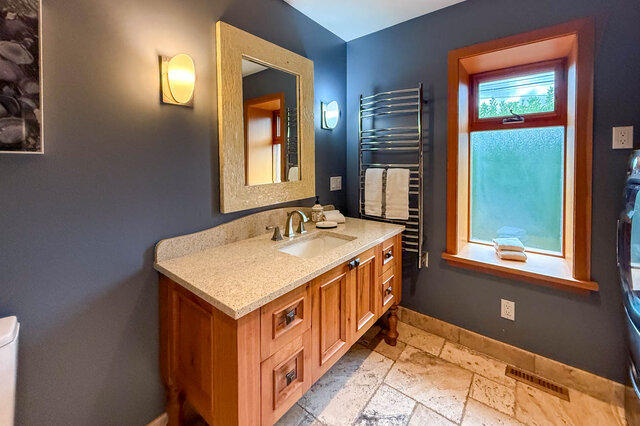 Spacious bathroom with granite countertops, wooden cabinets, and a window with frosted glass. - 3850 Point Grey Road, Vancouver West Side