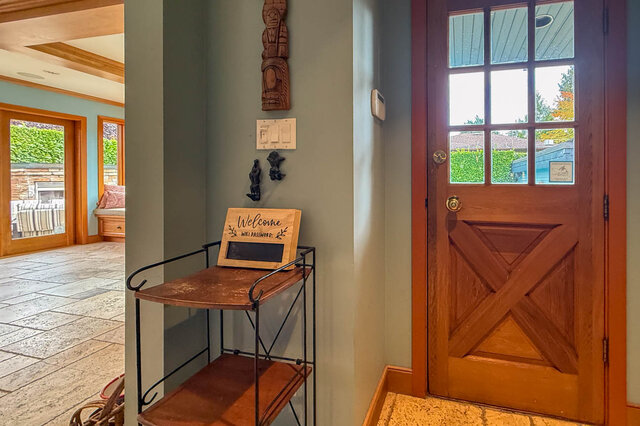 Foyer with wooden door, welcome sign, and decorative totem pole. - 3850 Point Grey Road, Vancouver West Side