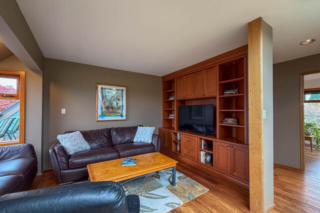 Spacious living room with hardwood floors, a large sectional sofa, and a built-in entertainment center. - 3850 Point Grey Road, Vancouver West Side