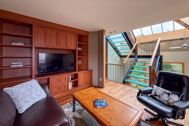 Spacious living room with built-in entertainment center, modern staircase, and cozy seating. - 3850 Point Grey Road, Vancouver West Side