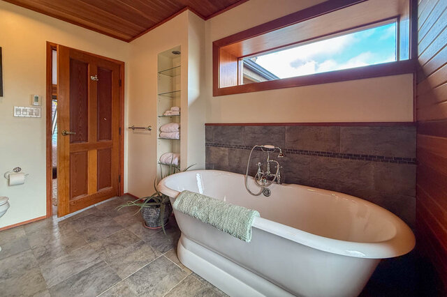 Spacious bathroom with a freestanding tub, wooden accents, and a large window. - 3850 Point Grey Road, Vancouver West Side