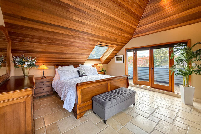 Spacious attic bedroom with wooden ceiling, skylight, and sliding glass doors leading to a patio. - 3850 Point Grey Road, Vancouver West Side