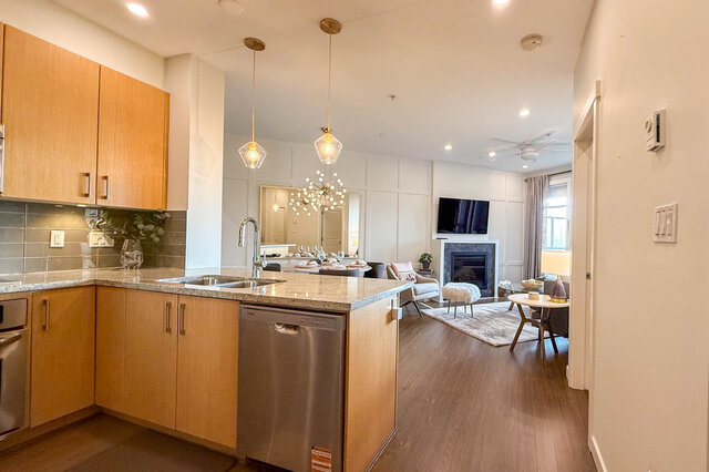Bright kitchen with granite countertops, hardwood floors, and a modern chandelier. - 526-119 West 22nd Street, North Vancouver
