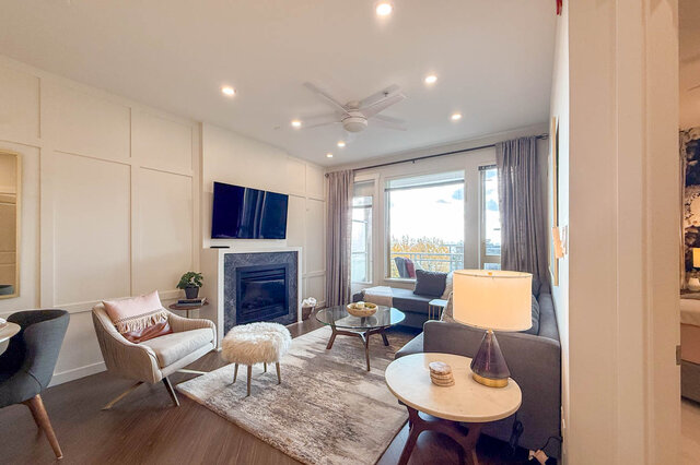 Spacious living room with hardwood floors, a cozy fireplace, and a large window offering a city view. - 526-119 West 22nd Street, North Vancouver