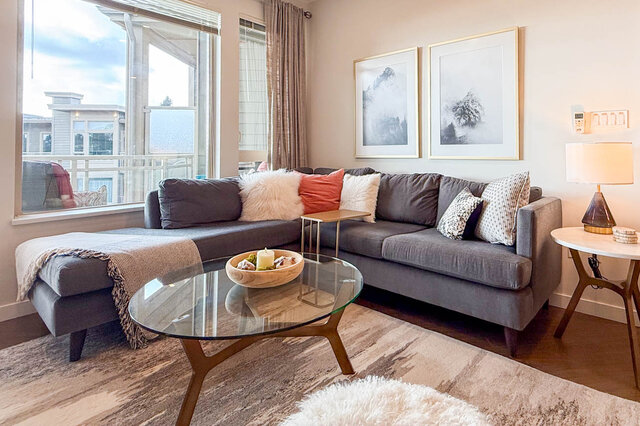 Spacious living room with modern furniture, large windows, and a cozy corner. - 526-119 West 22nd Street, North Vancouver