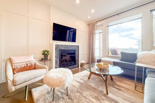 Spacious living room with a modern fireplace, sleek TV, and a cozy corner with a plush chair and throw pillow.