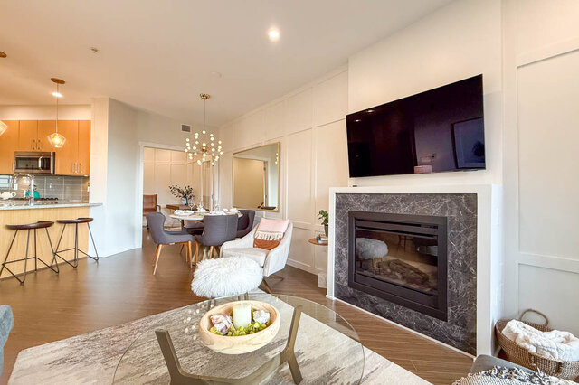 Spacious living room with marble fireplace, modern chandelier, and open-concept kitchen. - 526-119 West 22nd Street, North Vancouver