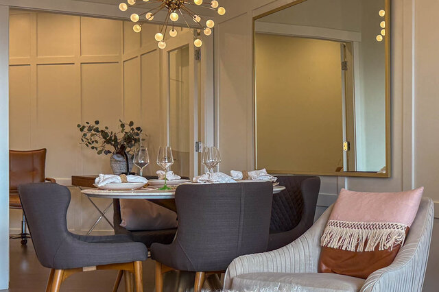 Elegant dining room with modern chairs, a round table, and a large mirror. - 526-119 West 22nd Street, North Vancouver