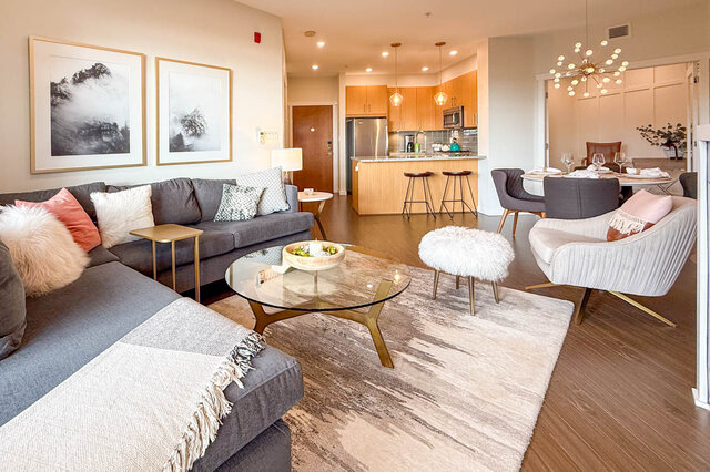 Open-concept living room with hardwood floors, modern furniture, and a cozy corner. - 526-119 West 22nd Street, North Vancouver