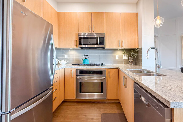 Bright kitchen with granite countertops, stainless steel appliances, and light wood cabinets. - 526-119 West 22nd Street, North Vancouver