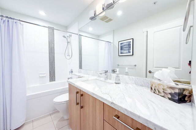 Spacious bathroom with marble countertops and wooden cabinets, offering a modern and clean look. - 526-119 West 22nd Street, North Vancouver