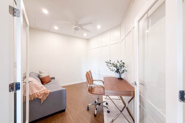 Spacious den with hardwood floors, a cozy sofa, and a stylish desk setup. - 526-119 West 22nd Street, North Vancouver