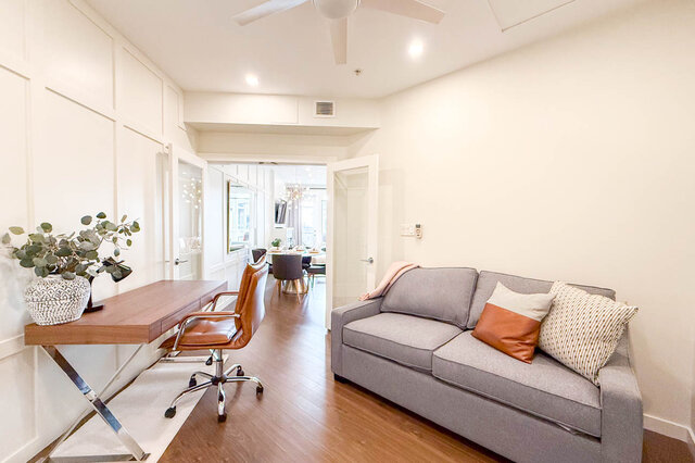 Spacious living room with hardwood floors, modern furniture, and a view of the dining area. - 526-119 West 22nd Street, North Vancouver