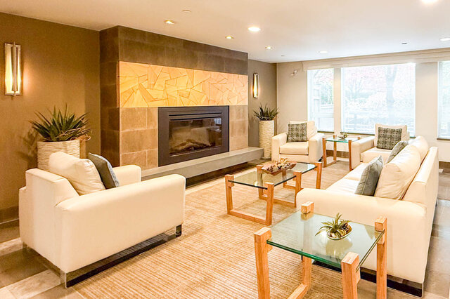 Spacious living room with modern fireplace, plush white furniture, and large windows. - 526-119 West 22nd Street, North Vancouver