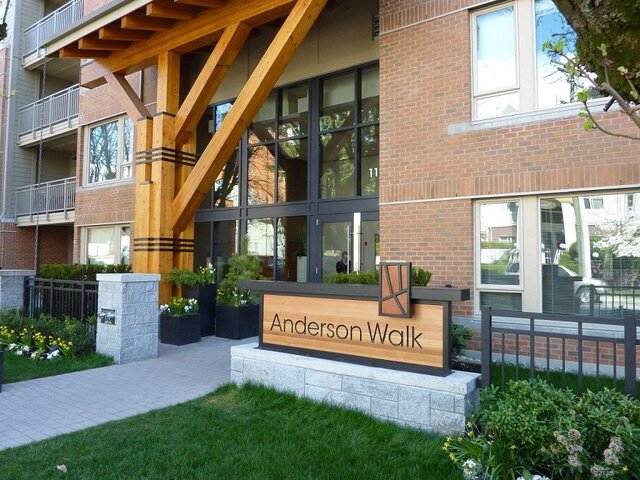 Furnished 1-bedroom + den condo with modern design, wooden beams, and a welcoming Anderson Walk sign. - 526-119 West 22nd Street, North Vancouver