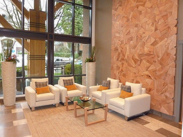 Spacious living room with modern furniture, large windows, and a unique wooden wall. - 526-119 West 22nd Street, North Vancouver