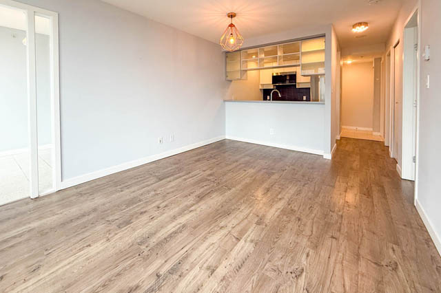 Open-concept living room with hardwood floors and a view into the kitchen. - 1011- 939 Expo Blvd., Vancouver Downtown
