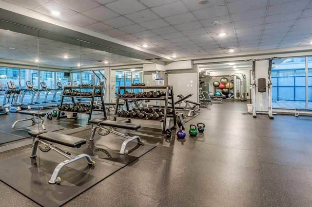 Spacious, well-equipped gym with weight racks, exercise mats, and kettlebells, perfect for fitness enthusiasts.