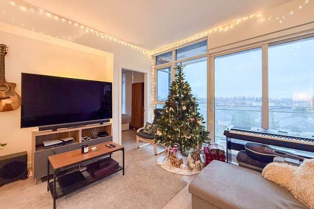Spacious living room with a Christmas tree, large windows, and a cozy sofa, perfect for holiday gatherings. - 407-2435 Kingsway, Vancouver East Side