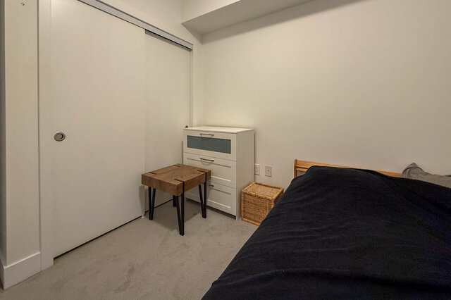 Spacious 1-bedroom + den with cozy bedding, wooden furniture, and a sleek white dresser. - 407-2435 Kingsway, Vancouver East Side