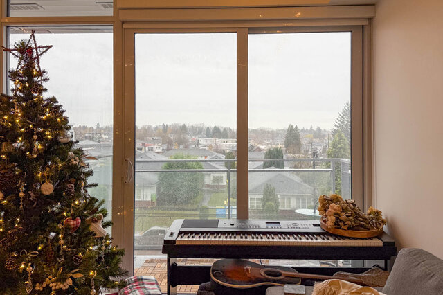 Bright living room with a decorated Christmas tree, city view, and piano. - 407-2435 Kingsway, Vancouver East Side