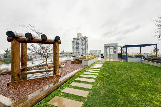 Spacious rooftop garden with lush grass, wooden pergola, and city views. - 407-2435 Kingsway, Vancouver East Side