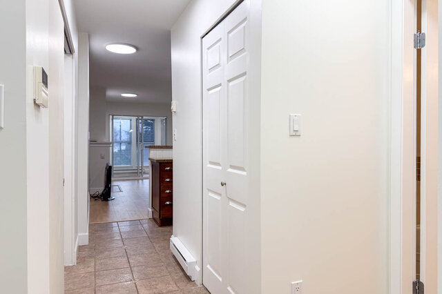 Spacious hallway leading to a cozy den with hardwood floors and a kitchen counter in the background. - 304-3637 West 17th Ave, Vancouver West Side