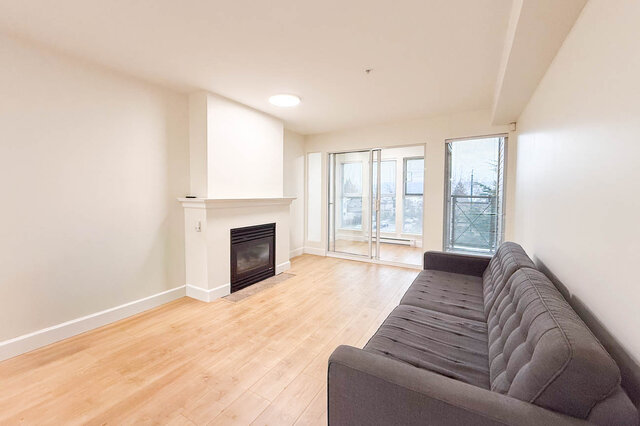 Spacious living room with hardwood floors, a cozy fireplace, and sliding glass doors leading to a city view.