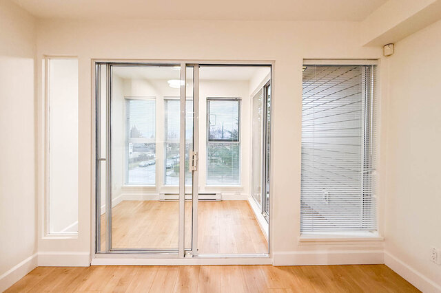 Bright living room with large sliding glass doors, hardwood floors, and a city view. - 304-3637 West 17th Ave, Vancouver West Side